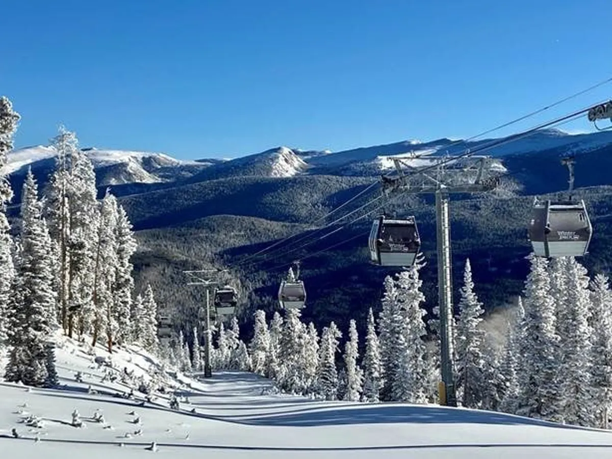 A wintery exterior scene featuring snow-covered trees, a gondola gliding over the landscape, and a breathtaking mountain range in the background. The image captures the essence of ski and snowboard adventures with the resort atmosphere front and center.
