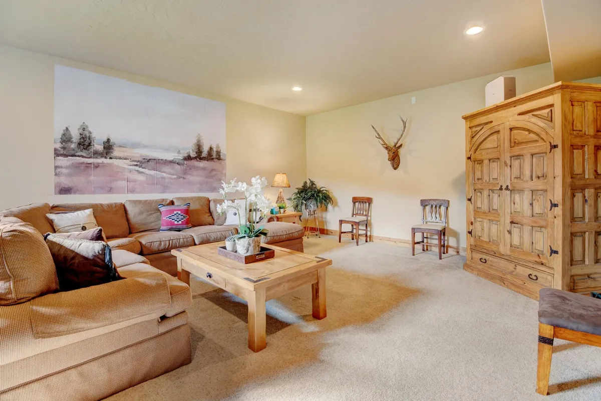 A cozy living area with a sofa adorned with decorative cushions, large wall artwork, a wooden cabinet, and a warm lamp. The arrangement is ideal for intimate family activities like board games, crafts, or relaxed conversation.